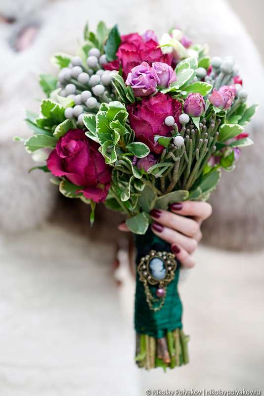 Букет невесты из малиновых и розовых роз, серой брунии и зеленого лигуструма, декорированный темно-зеленой лентой и брошью Камея  - фото 2548115 Фотограф Николай Поляков