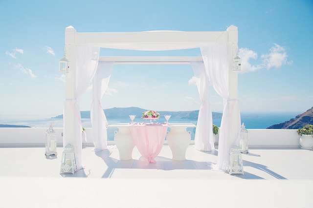 Квадратная арка, задрапированная белой легкой тканью, со столиком для росписи с букетом цветов - фото 1108189 Свадебное агентство Wedding in Santorini