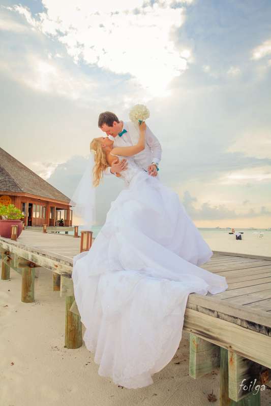 На пирсе на берегу моря, жених наклонив невесту держит ее за талию, он в светлой рубашке, на ней фата и белое платье со шлейфом - фото 2153254 Фотограф Рябышкина Ольга