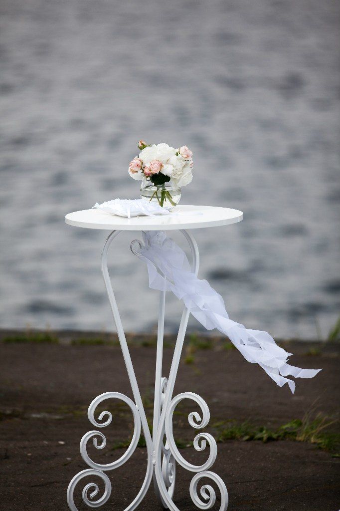 Белый столик для росписи, украшенный белой лентой, на котором стоит вазочка с цветами - фото 3460349 Свадебная студия "Бeze"