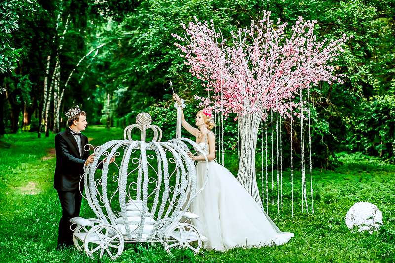 Жених и невеста стоят на фоне зеленых деревьев, белой кареты и бело-розового куста - фото 1787975 Свадебное агентство "Scarlet Star" - Алая звезда