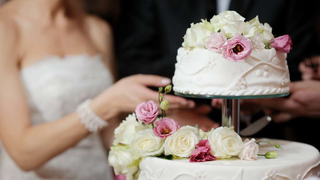 Жених с невестой, разрезающие белый 
свадебный торт, украшенный белыми-розовыми  сахарными розами - фото 956123 Невеста01