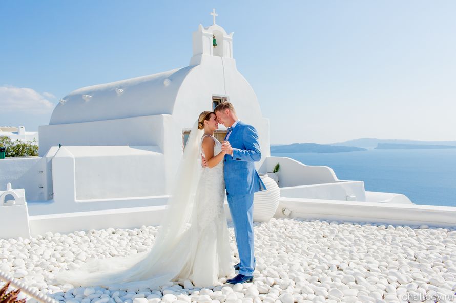 Жених и невеста, взявшись за руки, стоят на белом здании на фоне голубого неба - фото 3415327 Фотограф и стилист Александр и Элина Чальцевы