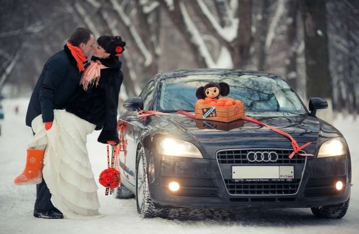 Черный "Audi", украшенный оранжевой лентой с мандаринами на капоте, на фоне зимнего леса и счастливой пары в костюмах с - фото 1449335 aniska