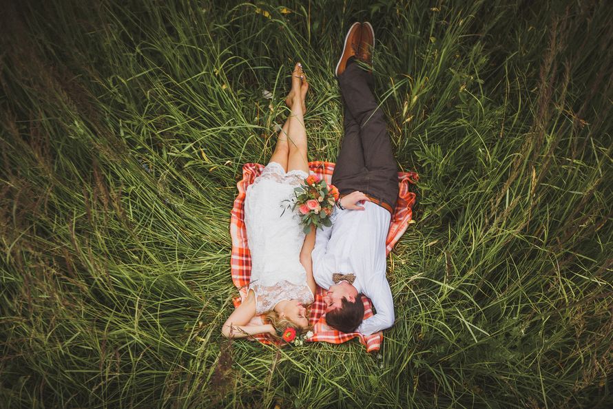 Жених и невеста, прислонившись друг к другу, лежат в зеленой траве - фото 3151341 Свадебное агентство "Diamond Wedding"
