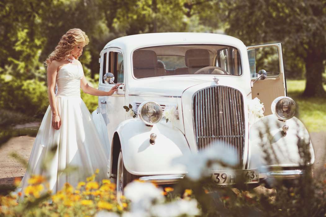 Белый ретромобиль украшенный белыми цветами на фоне зеленых деревьев, цветов и невесты. - фото 1225423 Света Кассина - фотограф
