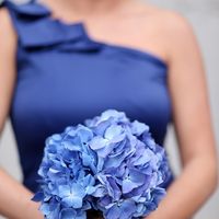 Подружка невесты в синем платье с косым рукавом на одно плече и с букетом в руках из голубых гортензий 