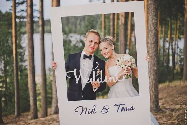 На фоне деревьев, жених и невеста держат в руках белую табличку и рамку - фото 2405104 Фотозоны и фотобутафория от Катерины Богославской