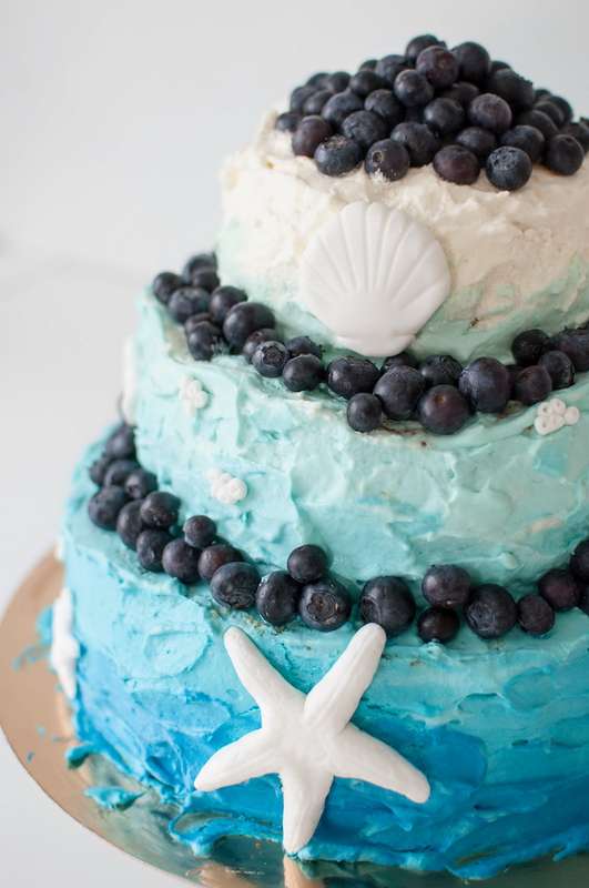 Многоярусный бело-голубой  свадебный торт, украшенный ягодами морскими ракушками с мастики. - фото 2725577 Кондитерская студия Тортификация
