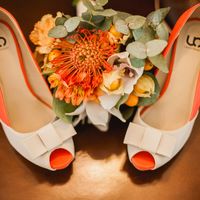 Открытые туфли невесты оранжево-белого цвета и вегетативный свадебный букет  на светло-коричневом  линолиуме