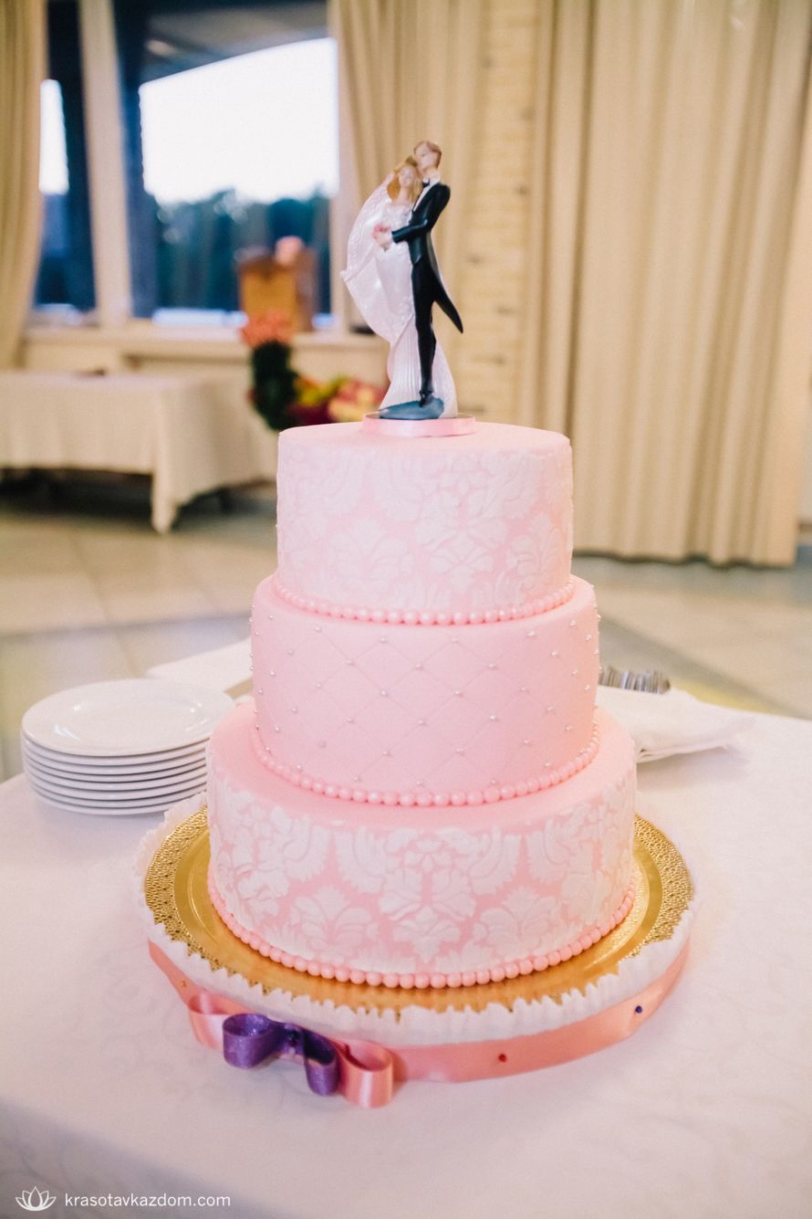 Трехъярусный торт розовый с белым узором на котором стоят фигурки жениха и невесты. - фото 3252635 Marri Alexeeva