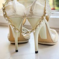 Молочно-белые открытые туфли на высоких каблуках для невесты и колье из позолоченного металла, кристаллов и жемчуга.