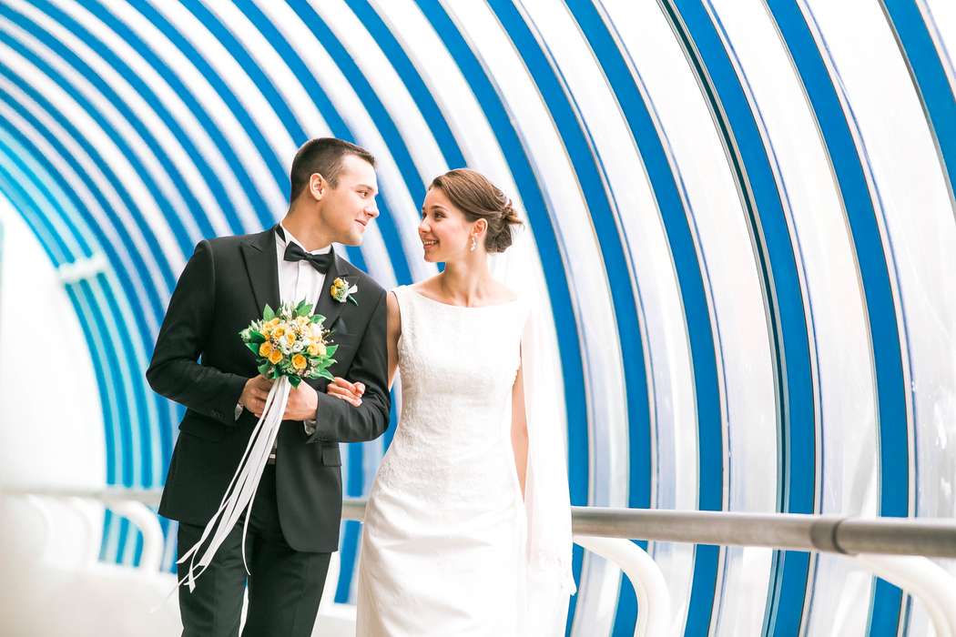 Жених и невеста, прислонившись друг к другу, стоят на фоне бело-голубой стены - фото 3353395 WeddingDays - декор, свадебная флористика