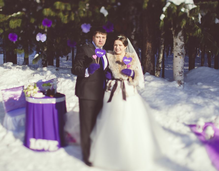 Жених и невеста в сиреневых варежках стоят возле столика с сиреневой скатертью и держат в руках таблички сиреневого цвета - фото 2969573 Свадебное агентство "Lucky Wedding"