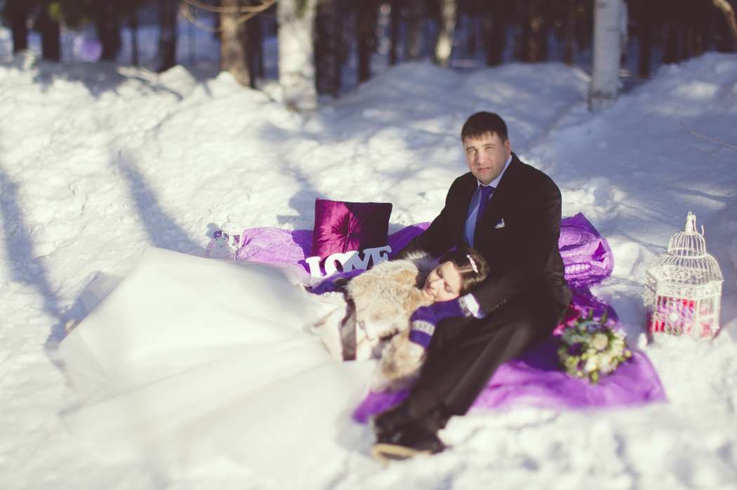На белом снегу, не сиреневом пледе сидят жених и невеста, я рядом табличка, подушечка и букет цветов - фото 2969579 Свадебное агентство "Lucky Wedding"