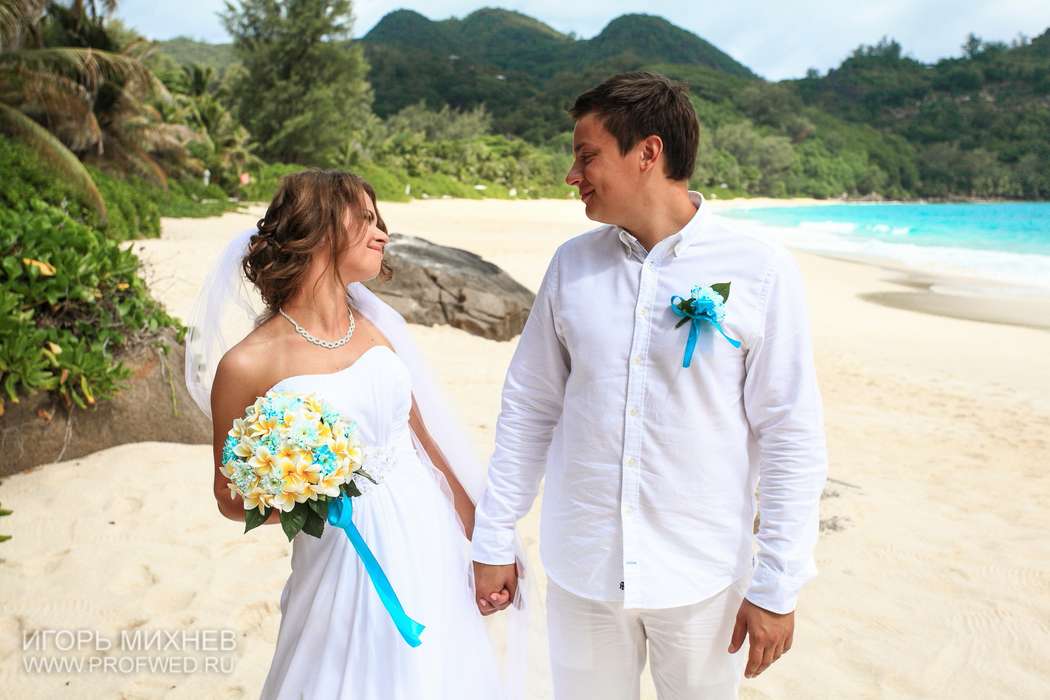 На пляже, стоят взявшись за руки жених и невеста, с улыбкой смотрят  в глаза, она в белом, открытом платье, он в белой рубашке и - фото 3535335 nastu_nastu
