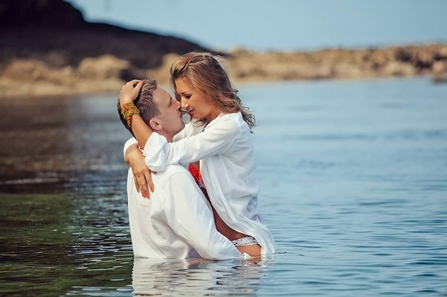 Окунувшись по пояс в воду, парень в белой рубашке обнимает девушку за талию и бедра, она одета в купальник и белую рубашку, - фото 3150209 Фотограф Третьякова Татьяна