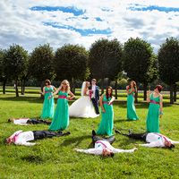 Жених в синем костюме и невеста в платье "принцесса", подружки в одинаковых зеленых длинных платьях с розовыми поясами и друзья в розовых галстуках на траве