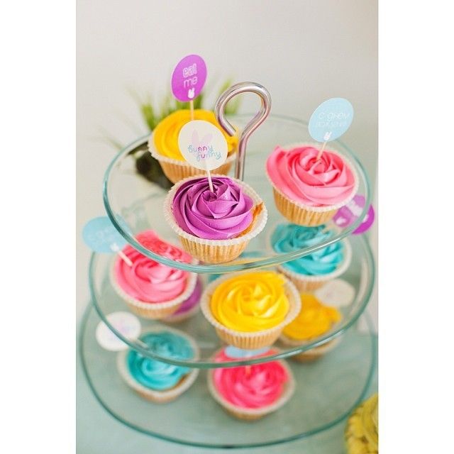 Капкейки, украшенные кремом желтого, розового, зелёного, фиолетового цвета, в бумажных формочках, расположены на стеклянной - фото 3297213 Nom-nom cakes - кондитерские изделия