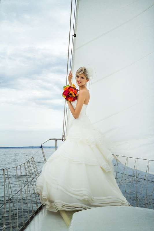 Невеста в платье А-силуэта цвета айвори с юбкой из рюш с отделкой лентами каждого яруса и букетом в красных тонах  - фото 3452425 Agatvideo - фото и видеосъёмка
