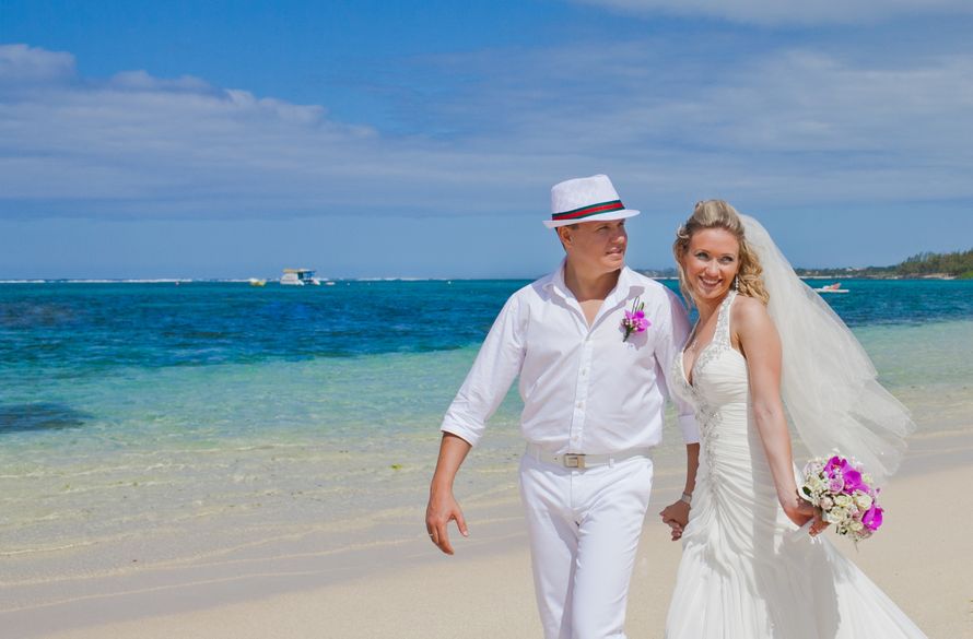 По пляжу идут жених и невеста, держась за руки, он в белой шляпе и белом костюме, она в белом, длинном платье со шлейфом и - фото 1866325 Фотограф Яна Яворская