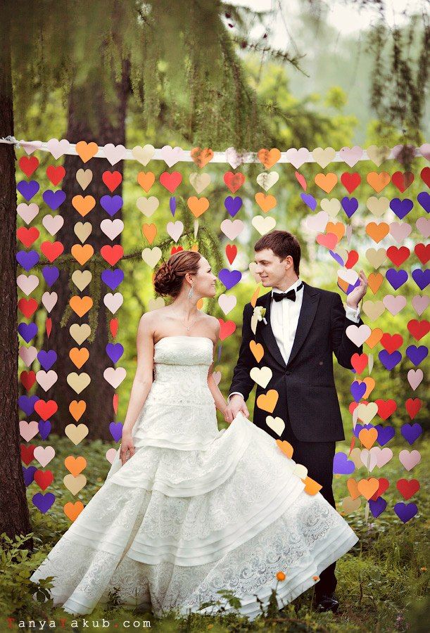 Летняя фотосессия молодоженов под свадебной аркой, украшенной свисающими разноцветными сердечками. Невеста в открытом  длинном - фото 499754 Невеста01