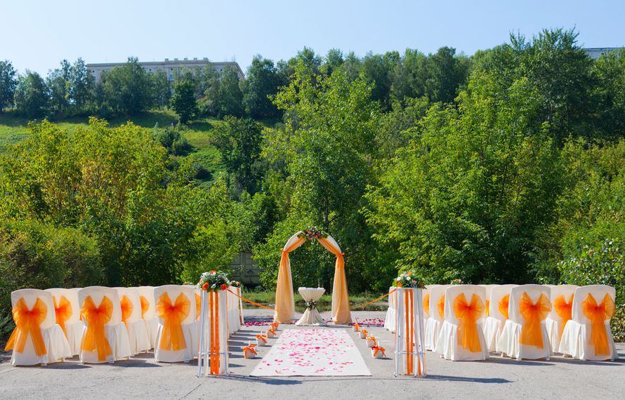 Классическая подковообразная свадебная арка обвитая живыми цветами, задрапированная белой и оранжевой тканью, на фоне стульев для - фото 3457815 Невеста01