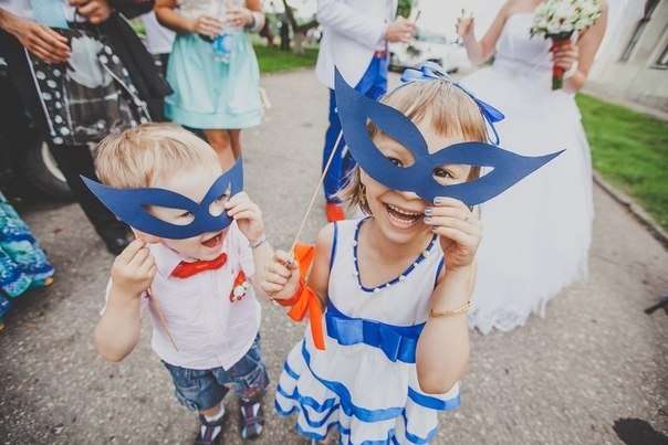 Мальчик с девочкой на свадьбе в бело - голубых тонах в праздничных нарядах держат голубые маски на палочке - фото 1482365 Ведущий Денис Бондарков
