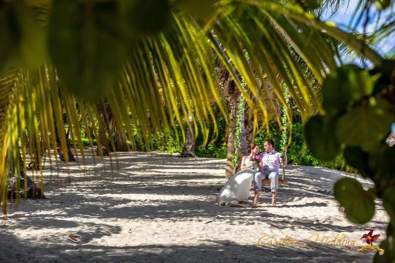 На тропическом пляже катаются на качелях молодожены, жених в светлых брюках и розовой рубашке, невеста в открытом белом платье - фото 3418465 Caribbean Wedding - свадьба в Доминикане