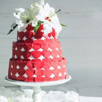 Свадебный торт ,в мастичном оформление в виде ярких сердец ,украшенный нежными ,живыми лилиями
