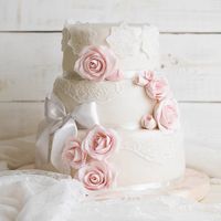 Элегантный свадебный торт, декорированный кружевом и розовыми розами.