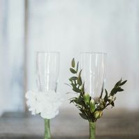 Живые цветы украшают бокалы для жениха и невесты