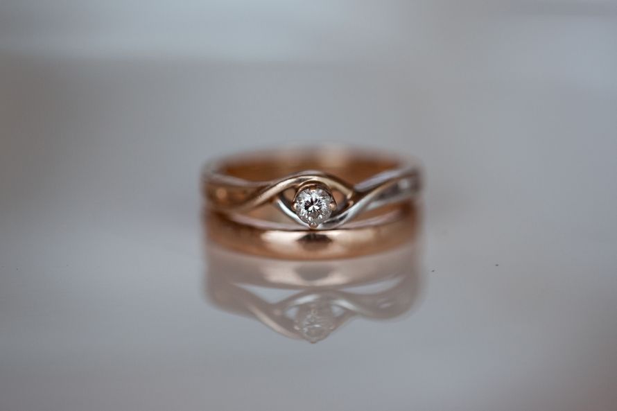 Обручальные кольца, одно из которых с бриллиантом на зеркальном фоне. - фото 1611201 Malena-Malena