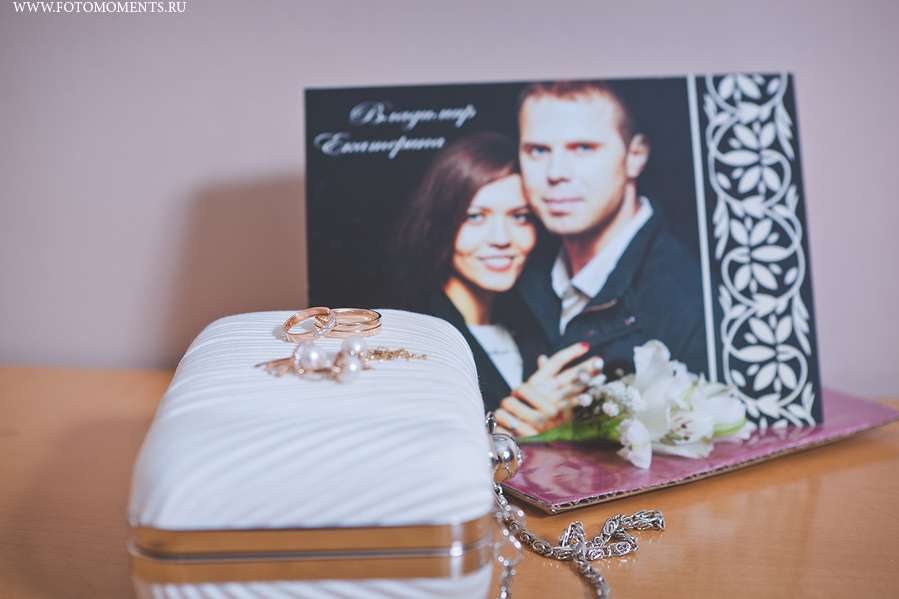 На столике рядом с фотографией жениха и невесты лежит небольшая белая сумочка-клатч на цепочке с жемчужными серьгами и золотыми - фото 1524209 Shanshin Yury фотограф
