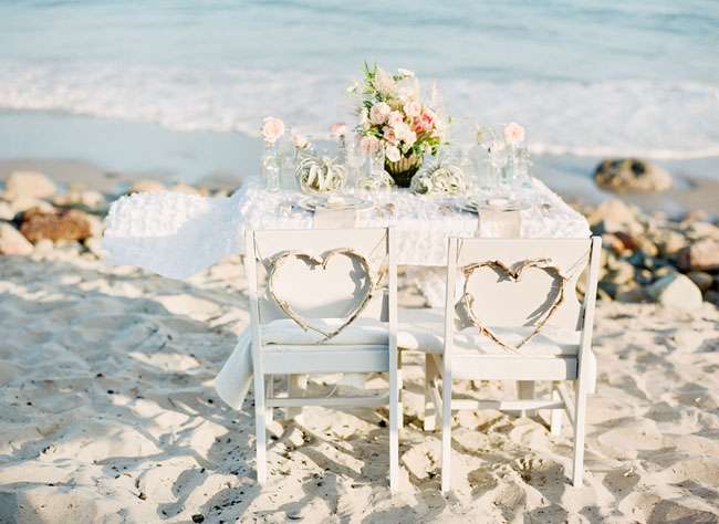 Оформление для фотосессии свадьбы на пляже с использованием белых стульев, украшенных сердцами из лозы, белого стола с цветами, - фото 1504037 elenasperanza